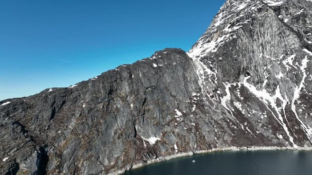 Dramatic Aerial Drone View of Massive Rocky Mountain Cliff Face Above Greenland Fjord Near Nuuk