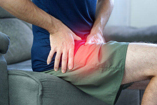 Unrecognizable man touching groin area suffering from hip osteoarthritis with red highlight