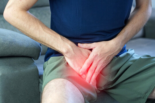 Unrecognizable man pressing hand on upper inner thigh suffering from groin strain pubalgia