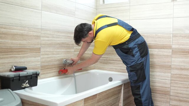 Plumber fixes faucet in modern bathroom during afternoon