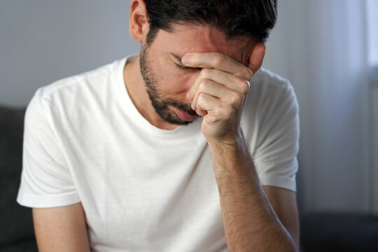 Chronic Migraine concept. Unidentified man covering face suffering from severe chronic migraine.