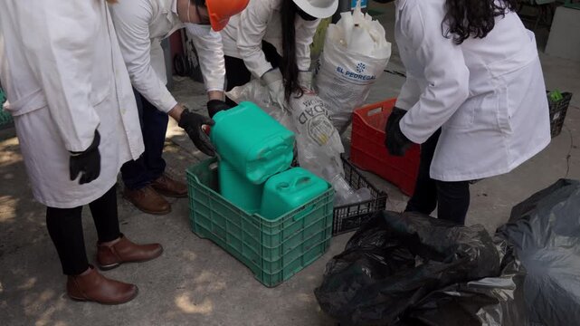 Workers at a recycling plant deposit empty High-Density Polyethylene (HDPE) containers into crates for processing into eco-friendly construction materials like eco-bricks.