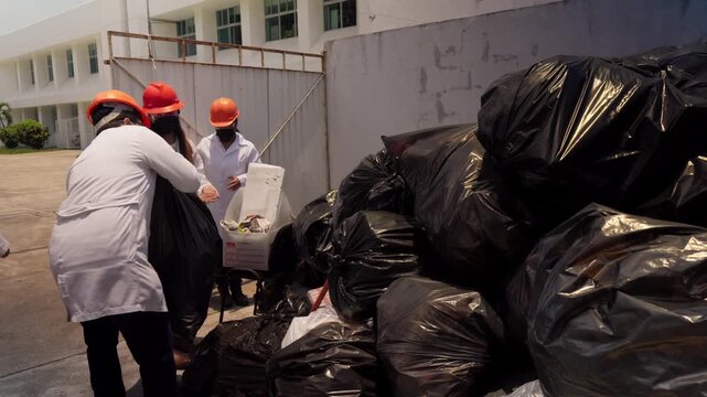 Workers in lab coats, safety helmets, and face masks diligently sort and move plastic waste bags at a recycling plant in Mexico City, contributing to eco-friendly construction materials production.