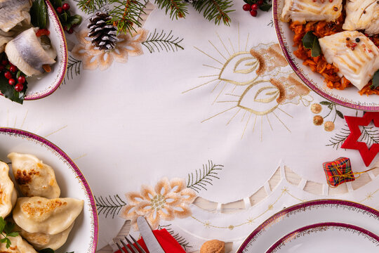 Classic Christmas food medley on a decorated table. Fish, dumplings stuffed with cabbage and mushrooms, cheesecake, and ham.