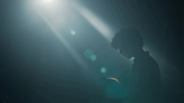 A lone individual stands bathed in a dramatic spotlight, evoking a profound sense of introspection and solitude amidst the darkness. ..Created with Generative AI, not depicting real subjects.