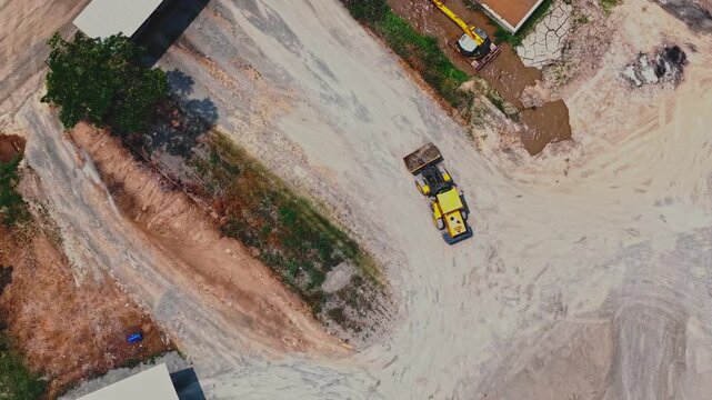 Aerial view of a yellow construction vehicle working on a gravel site in Yogyakarta, Special Region of Yog, Indonesia.