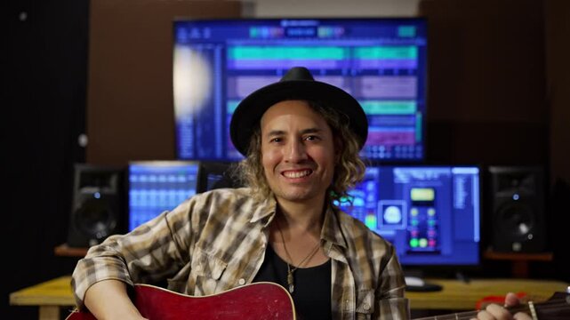 Independent music producer smiling with guitar in studio