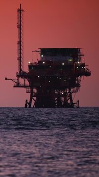 Oil drilling platform at sunset by the ocean