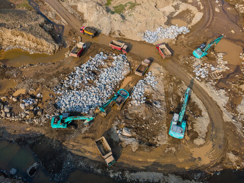 Aerial View of Heavy Machinery work in a Large-Scale Rock Ore Quarry During Morning Viewed from Above in Dawuhan Kulon, Central Java, Indonesia.