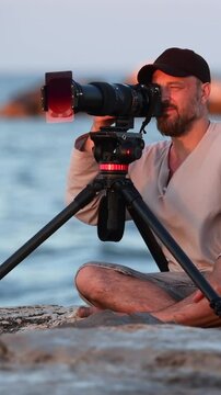 Man using a telephoto lens on a beach at sunset