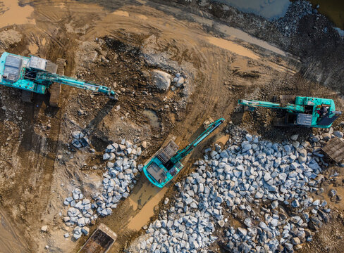 Aerial View of Heavy Earthmoving Machinery Group of Excavators Working in a Large-Scale Rock Ore Quarry. Mining Site Work from Above.