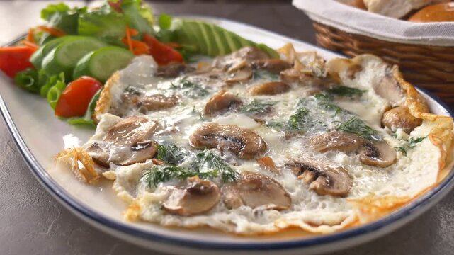 Healthy mushroom omelet with fresh herbs and garden salad served on white plate for breakfast or brunch.