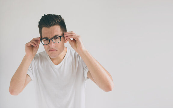 Close up portrait of a funny man with eyeglasses. Weird young guy has eyesight problems. The concept is isolated on a white background.