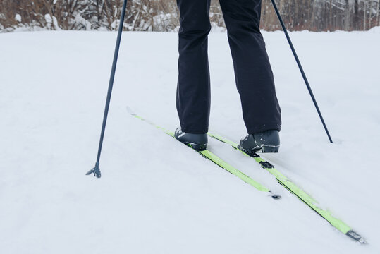 young man does skiing in snowy field, black clothes, hold ski poles in hands, cloudy winter day, healthy lifestyle