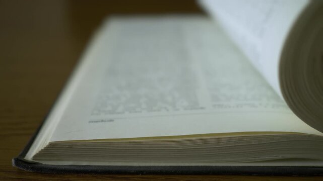 Flipping dictionary pages with shallow depth of field, close-up shot