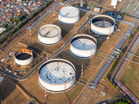 Aerial view of large industrial oil storage tanks and complex pipeline infrastructure at a refinery facility in Cilacap, Central Java, Indonesia.