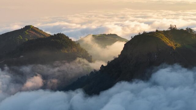 Aerial view of Dieng Plateau mountain peaks rising above a thick sea of clouds during the golden hour in Indonesia.