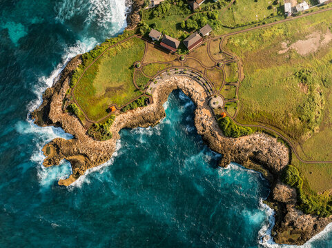 Aerial view of the rugged coastline and crashing waves at Devil's Tears on the island of Nusa Lembongan, Bali, Indonesia.