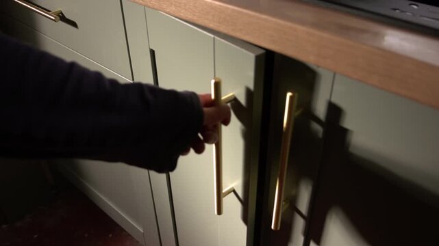 Hand opening green kitchen cupboard cabinet door
