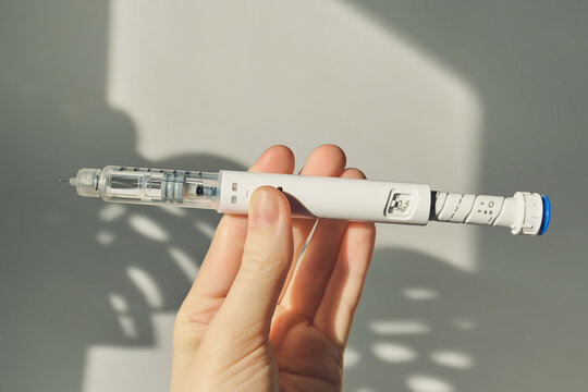 Hand holding GLP-1 injection pen with medication for weight management