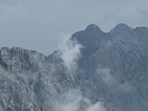 Aerial view of the rugged Apuan Alps marble mountains with jagged peaks and wispy clouds in Carrara, Tuscany, Italy.