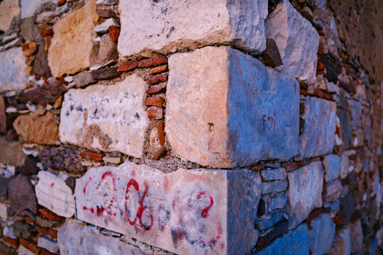 Architectural corner detail of an ancient stone wall featuring large limestone blocks and weathered bricks in warm twilight evening light
