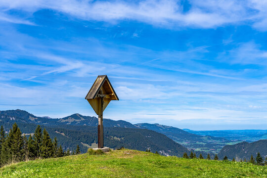 Beautiful panorama view of Allgaeu Alps with the wooden crucifix shrine near Schrattenwang Alpe on Sollereck in sunny summer day, Oberstdorf, Bavaria, Germany