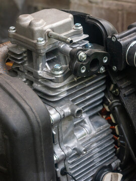 A detailed close-up shot showcasing the aluminum cylinder block, valve cover, and cooling fins of a compact four-stroke internal combustion engine, commonly used in portable generators or garden machi