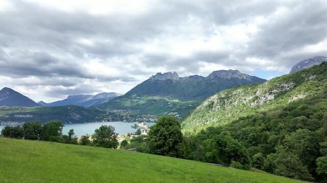 Scenic view of Lake Annecy and Duingt castle from a hill, French Alps, Haute-Savoie, France, Europe. Stunning landscape of the French Alps with Lake Annecy, Duingt castle and moving clouds, France, Eu
