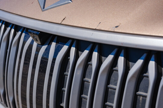 Close up view of the front tulip inspired vertical radiator grille and parking camera on a modern bronze Togg T10X electric crossover vehicle