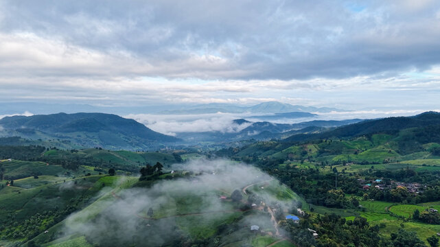 Aerial landscape view of rice terrace and wooden huts in mountains on cloudy morning
