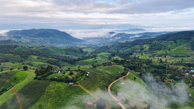 Aerial landscape view of wooden huts and dirt road in the rice terrace and mountains