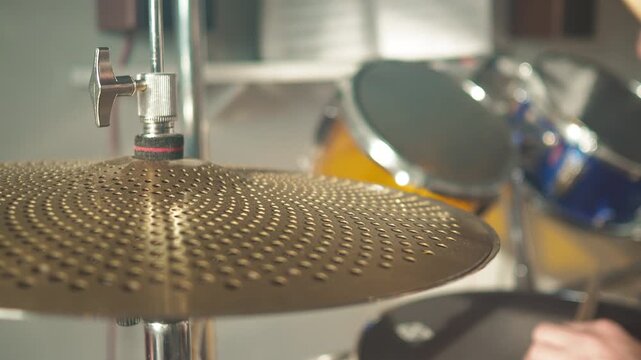 Drummer performs in a practice space while hitting cymbals and drums with focus on rhythm and technique