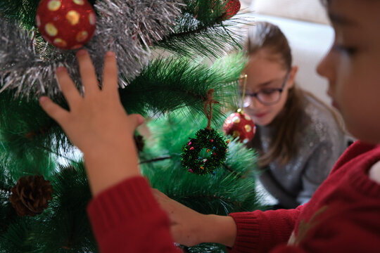 Children decorating christmas tree with ornaments for holiday season