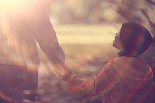 Parent and Child Holding Hands in Sunlit Autumn Forest