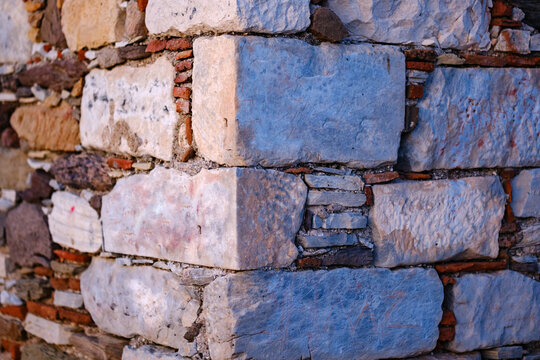 Historic stone wall corner detail showing ancient masonry with weathered limestone blocks and red brick fragments in abandoned rustic architecture