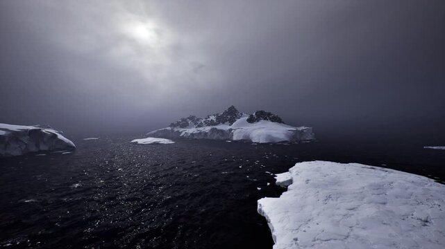foreground ice floe leading to distant cliffs across dark water, faint sun through clouds, cool sparkle on waves and sense of passage toward remote ridge
