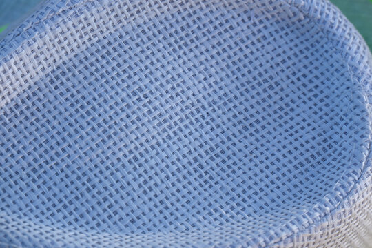Macro texture of a woven straw hat crown with circular spiral pattern.