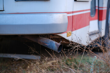 Rusted exhaust pipe under the rear bumper of a vintage retro Otomarsan bus parked on a field overgrown with dry vegetation © Bugra Kaan Ersoy