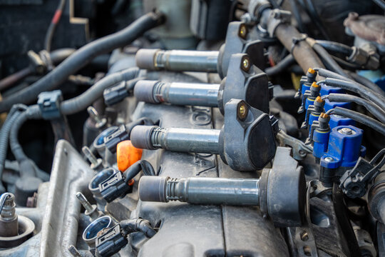 Four removed black plastic ignition coil packs resting horizontally across a dusty silver engine valve