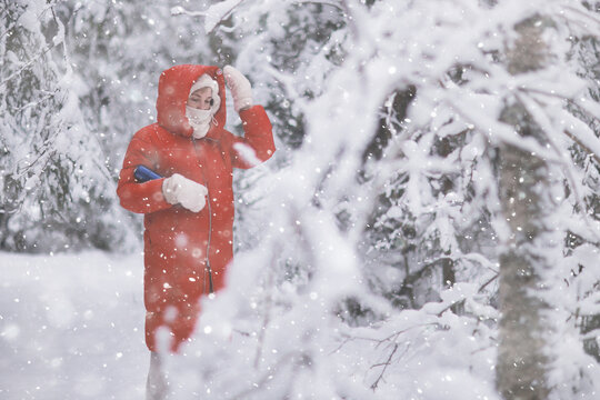 Snowy Walk: Person in Red Coat Enjoying Winter Wonderland in Snow-Covered Forest
