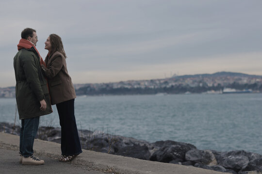 Romantic Couple Enjoying Moment by Serene Waterfront on Cloudy Day