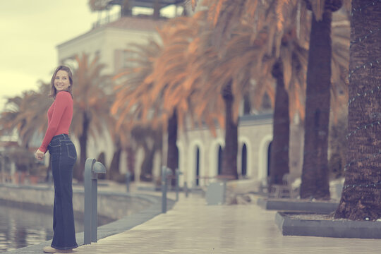 Woman in Red Top Strolling Along Waterfront Lined with Palm Trees