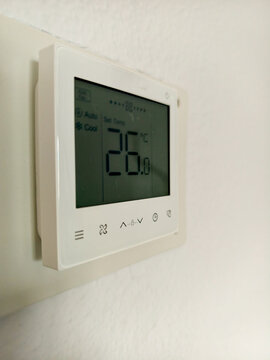 Digital wall thermostat displaying 26 degrees for home air conditioning control system
