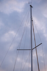 Tall sailboat mast and rigging standing upright against a moody overcast sky during tranquil nautical twilight hour © Bugra Kaan Ersoy