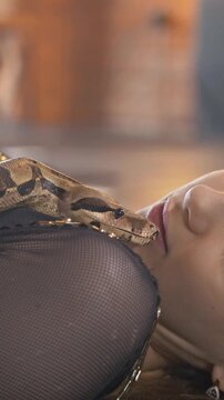 Young attractive dancer lying with python in a studio