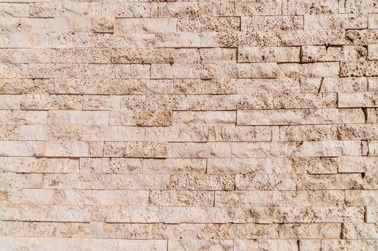 Stone brick wall displaying textured beige masonry surface