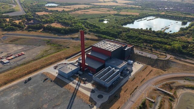 Aerial view of Rookery South ERF and Millbrook Power plant with industrial buildings, a tall red chimney, and surrounding landscape in Stewartby, England, United Kingdom.