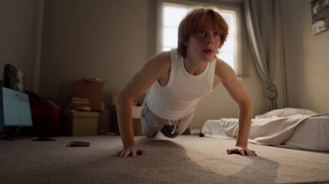 Caucasian man doing pushups during home workout. Footage suitable for youth fitness app promotions, physical training tutorials, and healthy lifestyle campaigns