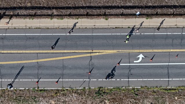 Aerial view of people walking and running along a road marked with traffic cones and lane lines in Boulder, Colorado, United States.